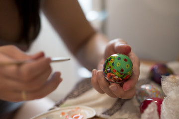a person draws a brush on an Easter egg with different colors