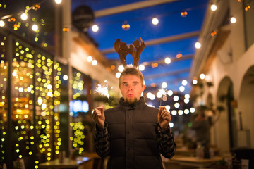Christmas and holiday concept - Happy man in Christmas deer costume with sparkler