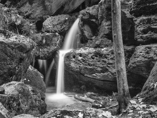 Schwarz-weiß Aufnahme eines kleinen Wasserfalls an einem Gebirgsbach.