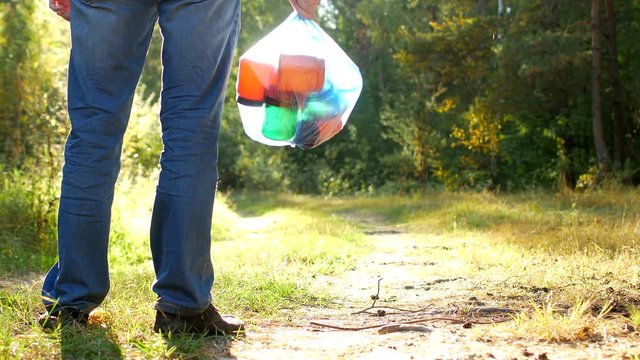 A man in a forest clearing stands with a package of garbage in his hands, a garbage collector, garbage and nature, close-up