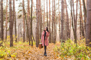 Fototapeta premium Weather, season, people concept - young woman in pink coat over the autumn nature background