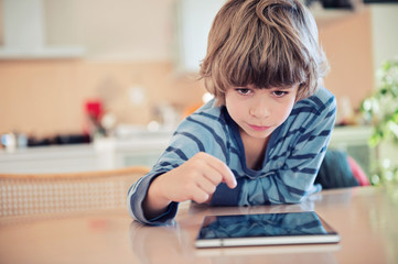 Naklejka na ściany i meble Little boy playing with digital tablet.