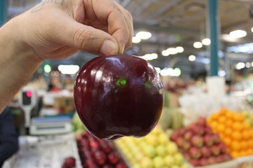 Dark-red apple ripe in hand in market