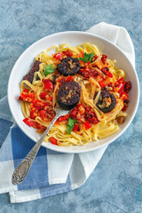 Fork in a plate with Italian pasta and blood sausages.