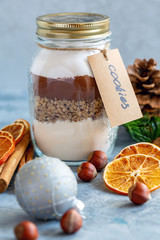 Glass jar with ingredients for baking chocolate nut cookies.