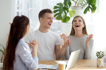 Three people sitting at the desk indoors. Happy millennial young married couple in real estate...