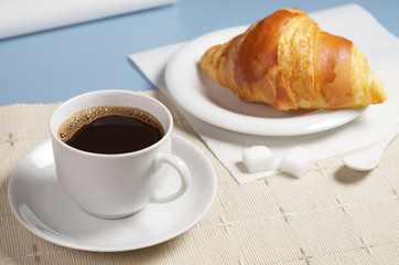 Coffee with croissant on table