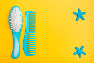 A set of plastic combs and two hairpins in the shape of a starfish on a yellow background. Top view