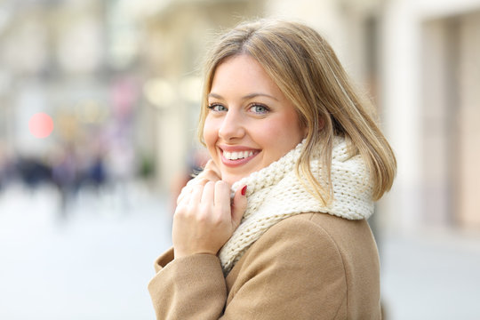 Happy woman posing looking at camera in winter in the street