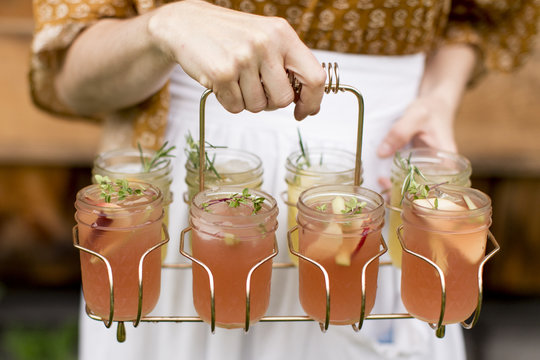 Woman holding drink caddy with cocktails in mason jars