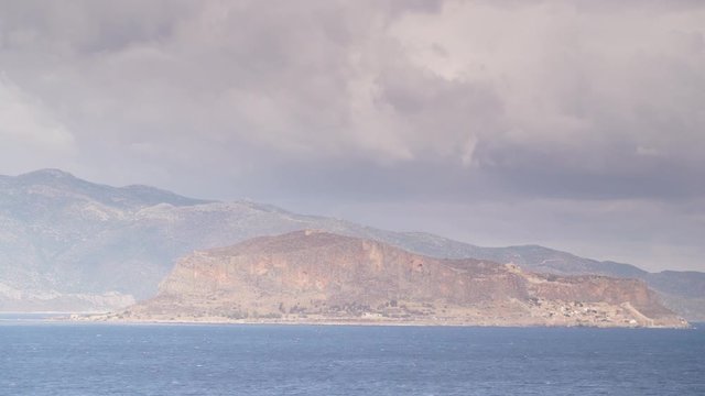 Greek island Monemvasia and cloudy sky, view from distance. Greece Peloponnese Lakonia, Time lapse