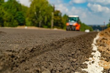 tamping asphalt by vibratory roller machine on the road. Close-up