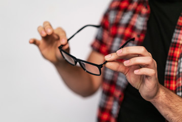 expensive eyeglasses with black rim are in the hands of man on a white studio background. Close-up