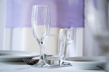 Empty plate, wine glasses, fork and knives on the table. Table setting