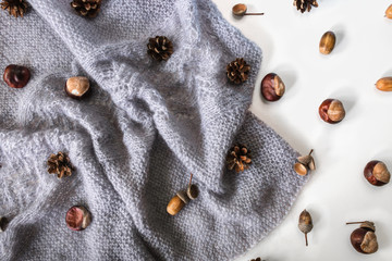 Diagonal grey knitwork with chestnuts, pinecones, acorns. Autumn cozy background.
