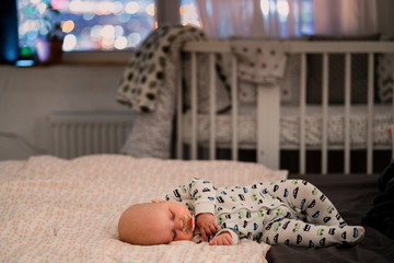 Adorable baby sleeping in a larger bed at night in pajamas. Bed linen for children. Interior...