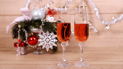 Новогодняя открытка, два фужера с розовым шампанским на фоне елки, игрушек, гирлянды