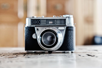 Analoge vintage Fotokamera steht auf Holztisch mit Namen eingraviert im Hintergrund verschwommen ein antiker Schrank