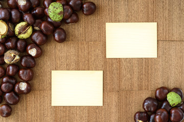 Top view of chestnuts and empty wooden cards on wood background as autumn set up.