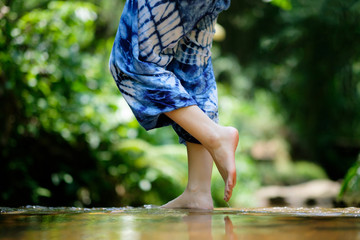 Female feet in water on green nature background.