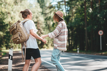 Fototapeta premium Couple travelers woman and man stand on road and looking forward to a joint journey. Lifestyle concept. Young happy family traveling adventure vacations