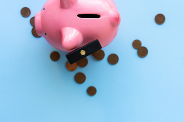 Top view of pink piggy bank with hammer and coins on blue background.