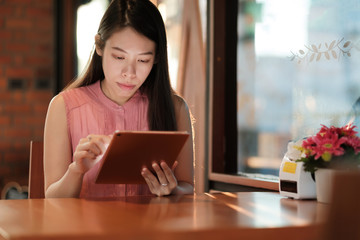 Woman looking on her tablet for social network in coffee cafe.
