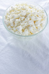 Cottage cheese. Cottage cheese on white background. Soft cheese in glassware on white napkin. Dairy product for breakfast. Copy space