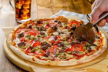 chef cuts pizza close-up with a round knife