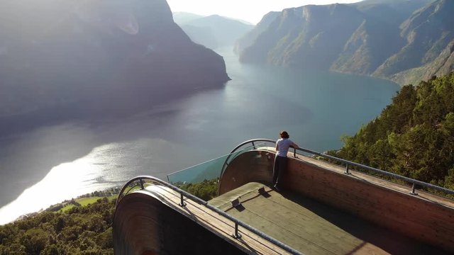 Aerial view. Tourist woman enjoying fjord view Aurlandsfjord landscape from Stegastein viewing point. Norway Scandinavia. National tourist route Aurlandsfjellet.