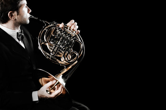 French horn player. Hornist playing brass orchestra music instrument