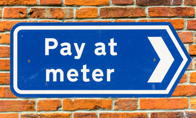 Pay At The Meter Arrow Sign Against Red Brick Wall, Exeter Devon England Spring 2016