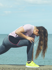 Woman stretching legs next to sea