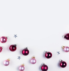 Christmas flat lay scene border with pink and violet glass balls, copy space on white table