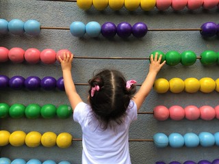 A cute girl playing with wooden abacus. Educational concept for kids. Learing to count. Math for...