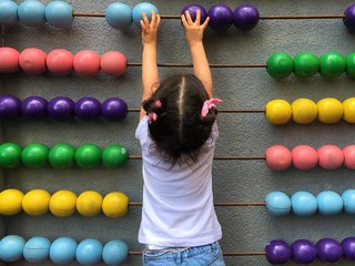 A cute girl playing with wooden abacus. Educational concept for kids. Learing to count. Math for...