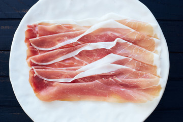 fresh italian sliced pork leg prosciutto crudo on a white plate top view
