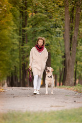 A woman walks with her labrador in the fall.