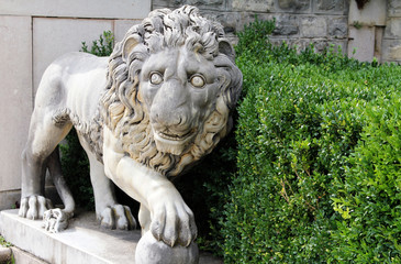 Fototapeta na wymiar Marble lion with a ball - ancient sculpture in the park of Peles Castle, Sinaia, Romania