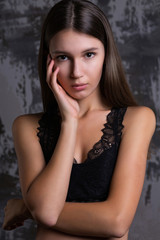 Test shoot of a lovely brunette girl posing in a black lace bra grey wall