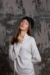 Fototapeta premium Test shoot of sensual brunette girl posing in stylish cap and knitted dress