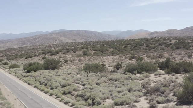 Aerial decend shot of a barren desert land with some small shrubs.