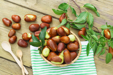 Obraz premium Wicker basket with fruits Ziziphus real, capiente, jujube, Chinese date, capiinit, jojoba, Chinese-date (lat.Ziziphus jujuba) on the table