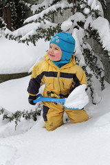 Fototapeta na wymiar Little boy cleans snow with a toy shovel
