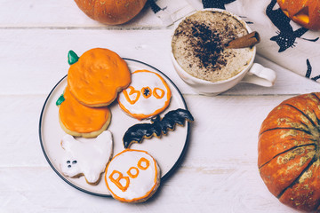 Halloween background with homemade Halloween cookies and pumpkins on the wooden table.