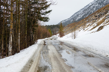 Mountain Road Covered in Melting Snow on a Winter Day