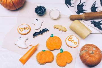 Halloween background with homemade Halloween cookies and pumpkins on the wooden table.