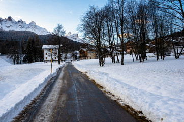 Fototapeta na wymiar Road to a Mountain Village Covered in Snow in The Alps at Sunset