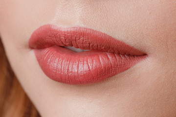 Close-up of make-up on lips, pink, woman smiles. Mouth ajar.