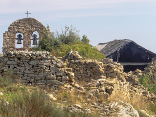 Bell gable among crumbling houses in a semi-abandoned village - Foncebadon, Castile and Leon, Spain